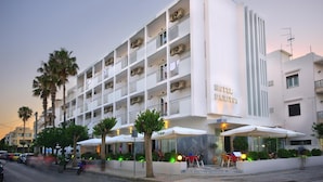 A multi-story hotel with balconies, outdoor seating, and palm trees. - Paritsa Hotel (Kos)