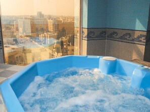 A hot tub with a city view through a window.