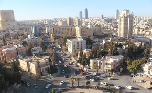 A cityscape with a mix of modern and traditional buildings, a central roundabout, and a clear sky.