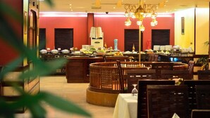 A dining area with round tables, a buffet with various food items, and a decorative chandelier. - Belle Vue Hotel (Amman)