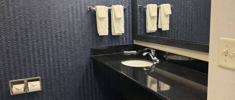 A bathroom with a black and white checkered floor, a sink, and two towels hanging on a rack.