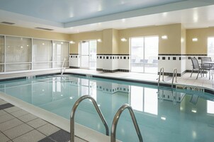 Una piscina con agua cristalina, escaleras de metal y paredes de azulejos.