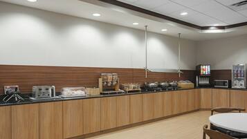 A modern kitchen area with wooden cabinets, a microwave, a coffee machine, and a refrigerator.