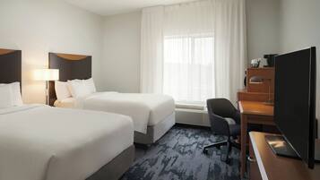 A hotel room with two beds, a desk with a computer, a chair, and a large TV.