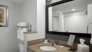 A bathroom with a granite countertop sink, a large mirror, a towel rack, and a toilet.