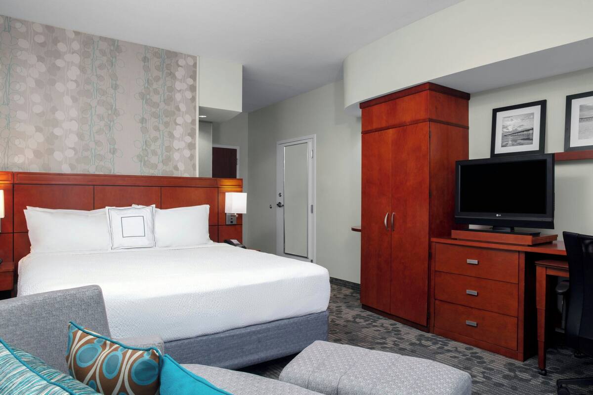Une chambre d’hôtel comprenant un lit, un bureau avec une télévision, une armoire et un canapé.