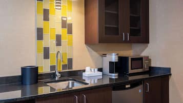A modern kitchen with a sink, coffee maker, and microwave.