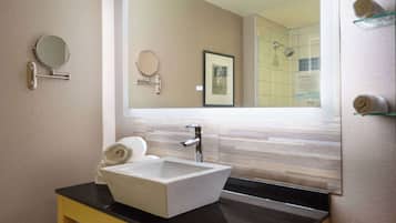 Un baño moderno con un espejo grande, un lavamanos y una toalla sobre la encimera.