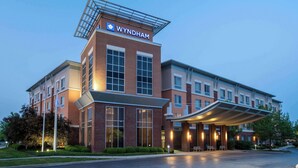 Ein Wyndham Hotel mit modernem Design, das einen markanten Eingang und einen überdachten Außenbereich bietet.