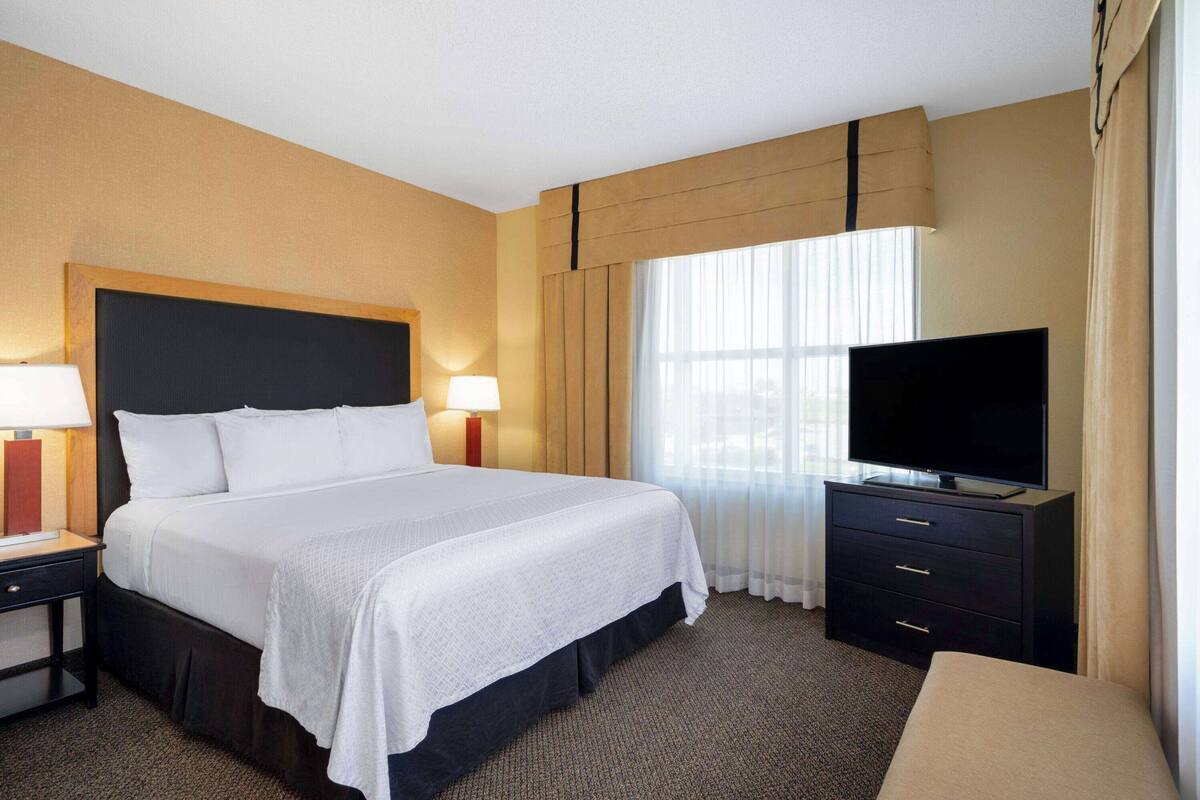 Une chambre d’hôtel avec un grand lit, des lampes de chevet, un téléviseur à écran plat et une commode.