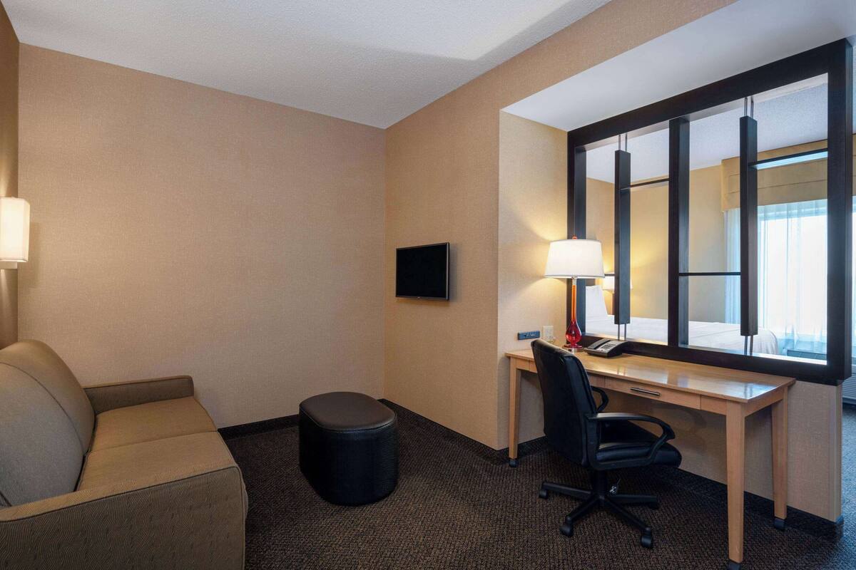 Une chambre d’hôtel avec un lit, un bureau, une chaise, une télévision et une lampe.