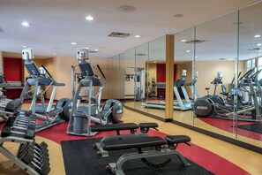 Un gimnasio con cintas de correr, elípticas y bancos de pesas.