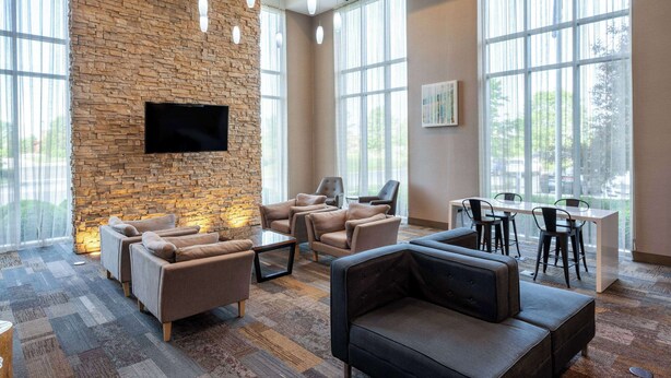 Eine geräumige Lobby mit Steinwand, bequemen Sitzgelegenheiten, einem Flachbildfernseher und großen Fenstern mit Blick ins Freie.