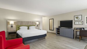 Une chambre d’hôtel avec un lit, une télévision, un bureau et une chaise rouge.