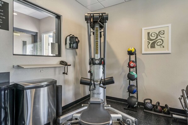 A gym with a cable machine, weight plates, and a mirror.