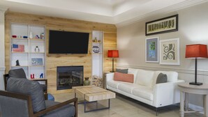 Un salon moderne avec une cheminée, un téléviseur à écran plat, un canapé blanc et une table basse.