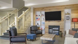 Un salon moderne avec un escalier, un téléviseur à écran plat et une cheminée.