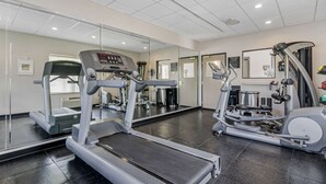 Une salle de sport équipée de tapis de course, de vélos elliptiques et d’un appareil d’aviron.