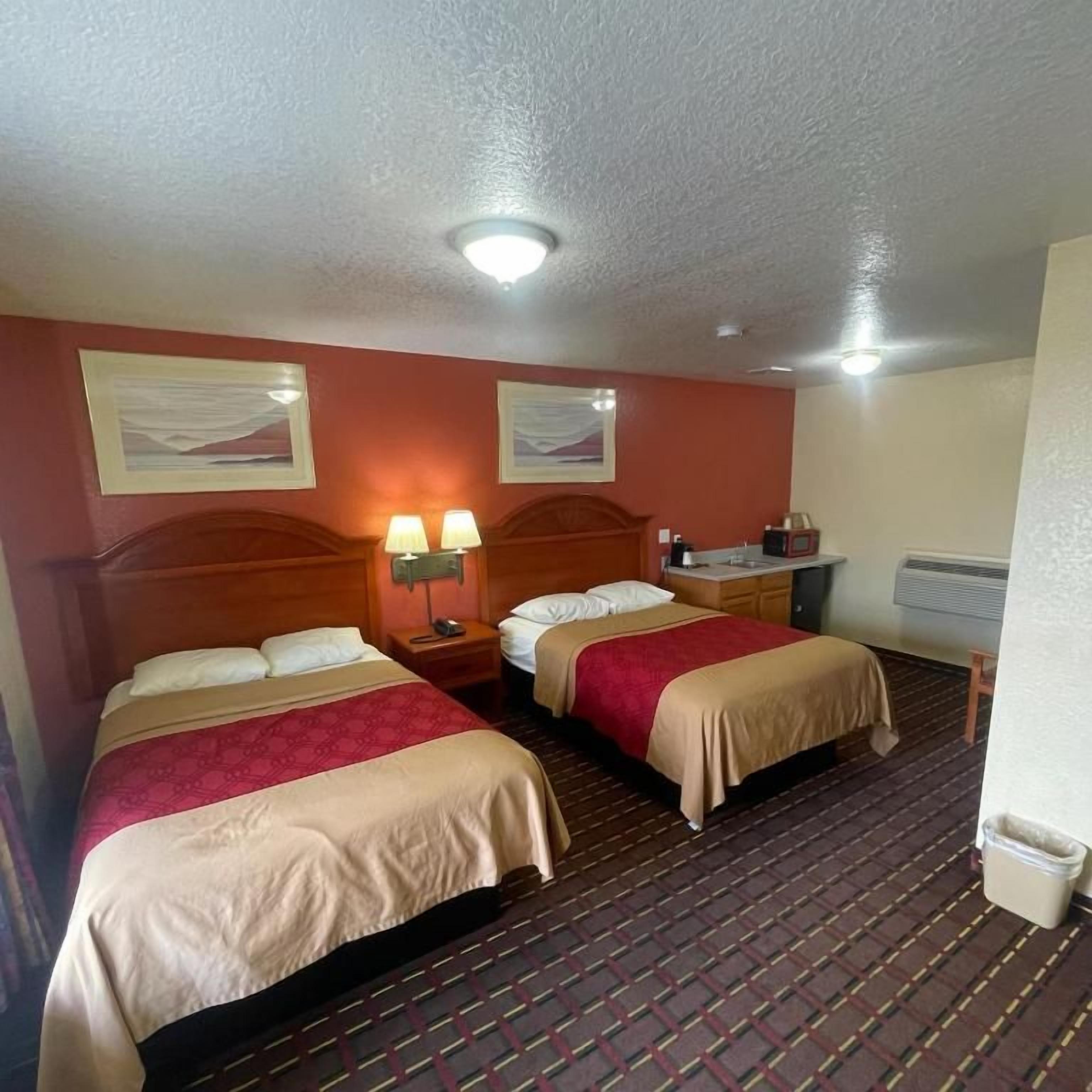 Une chambre d’hôtel avec deux lits, une table de chevet, une lampe et un radiateur.