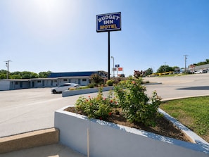A motel sign, a parking lot, and a building with a blue roof. - Budget Inn Madill (Madill)