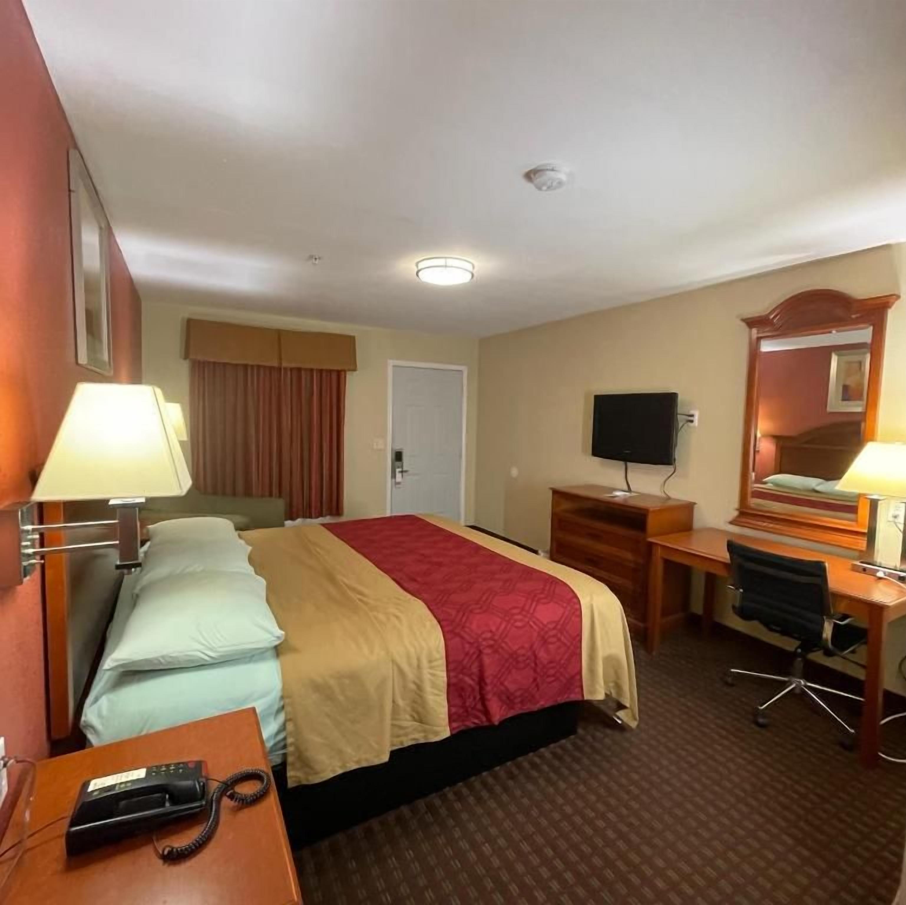 Ein Hotelzimmer mit Bett, Schreibtisch, Stuhl und Fernseher.