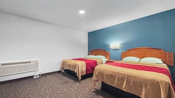 Hotellihuone, jossa on kaksi sänkyä, seinään kiinnitetty lämmitin ja kuviollinen matto.