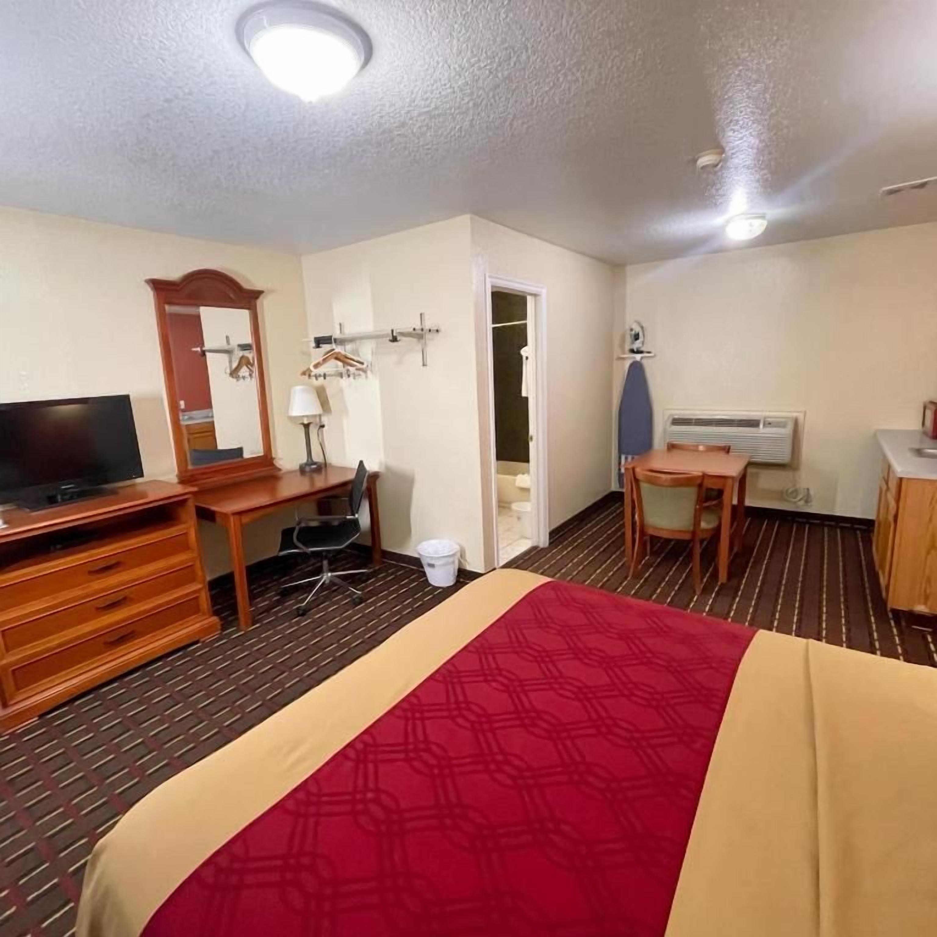 A hotel room with a bed, a desk, a television, a chair, a wardrobe, and a bathroom door.