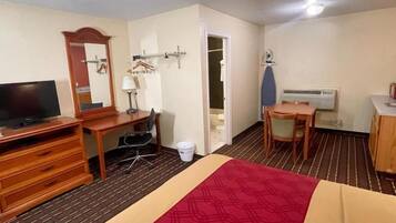 A hotel room with a bed, a desk, a television, a chair, a wardrobe, and a bathroom door.