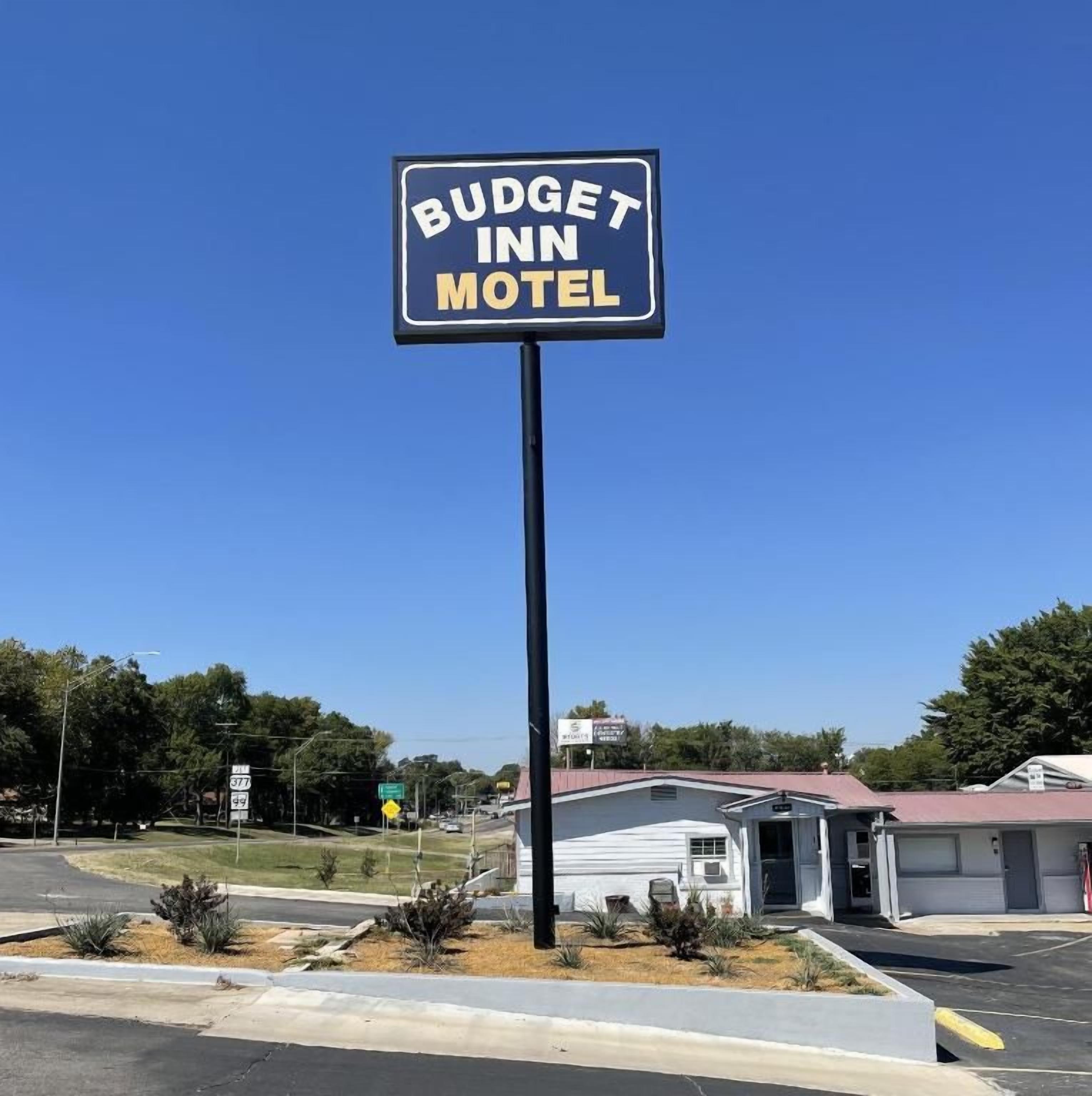 Letrero del motel Budget Inn con un cielo azul despejado de fondo.