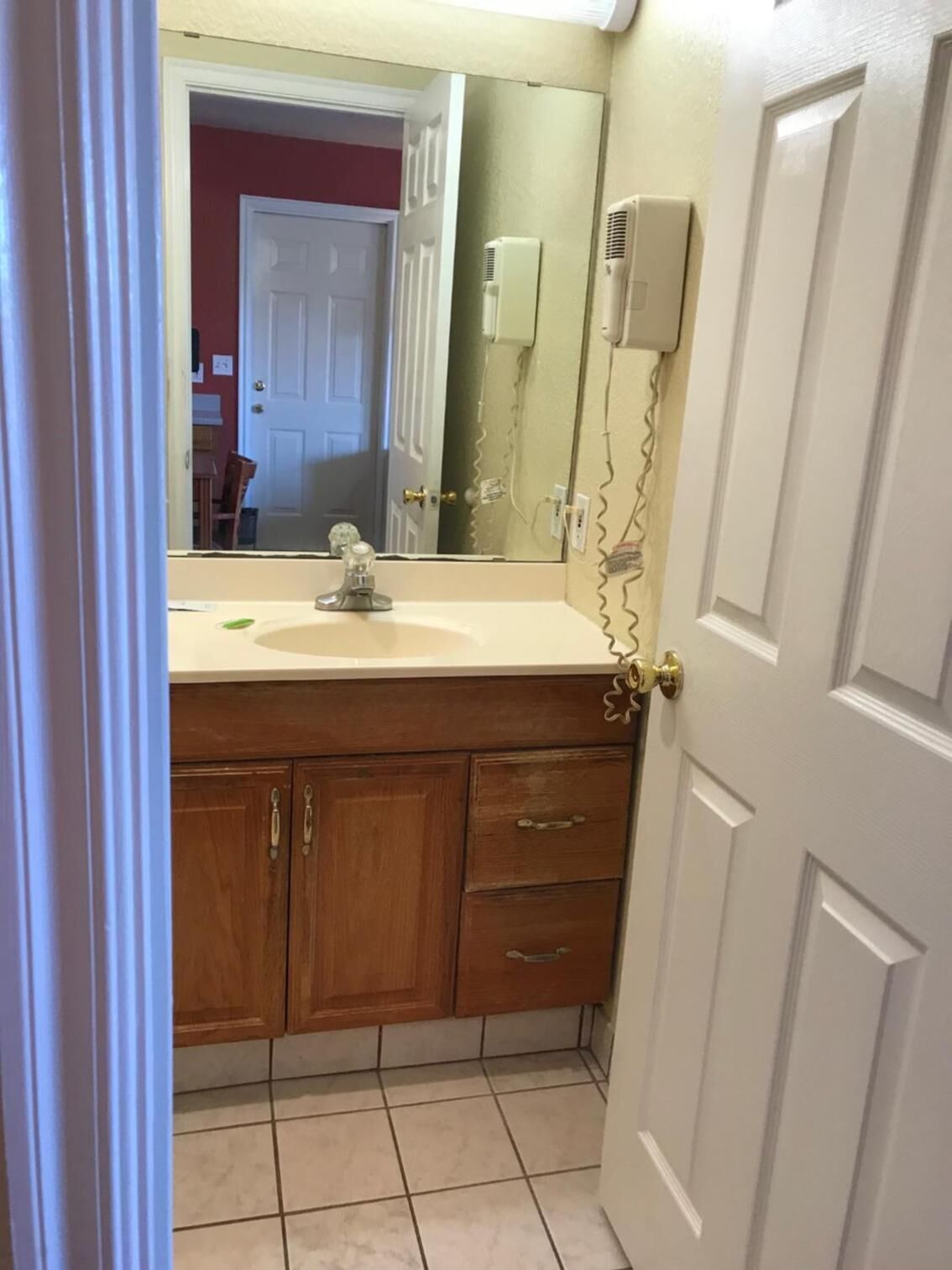 A bathroom with a white sink, wooden cabinets, and a mirror.