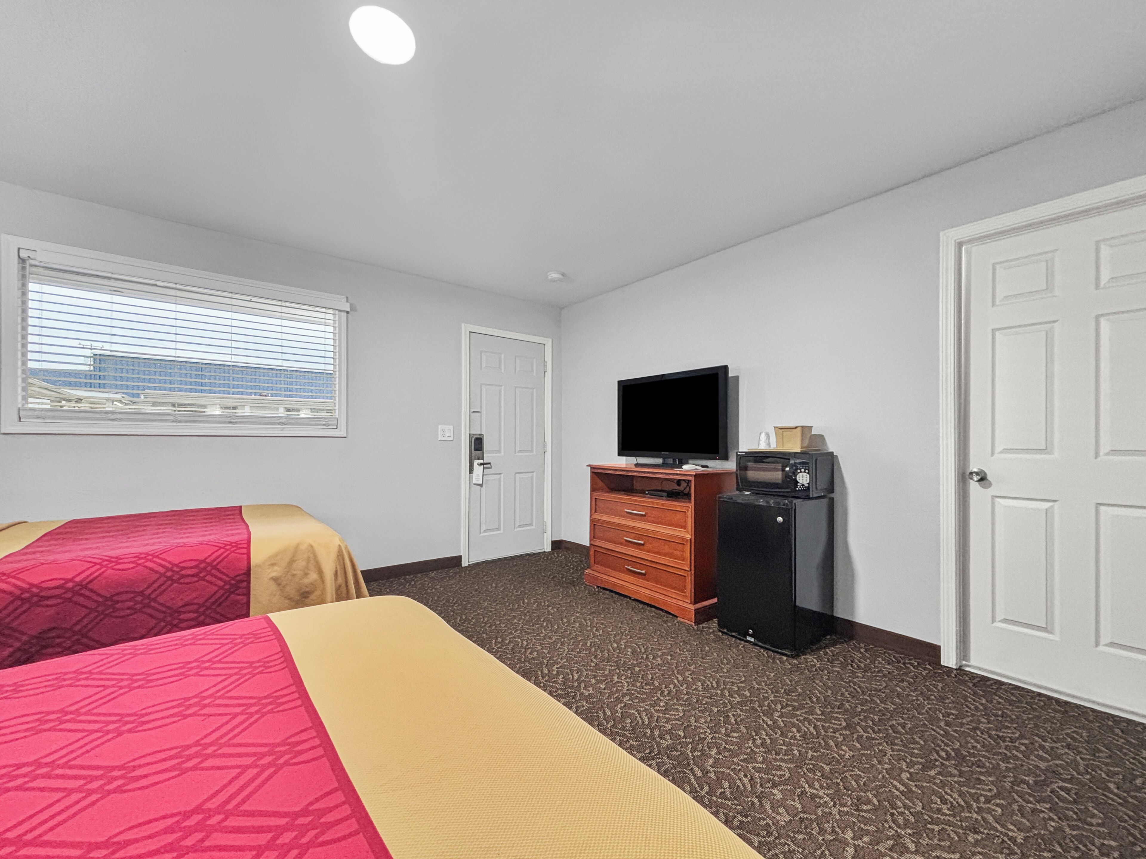 A hotel room with two beds, a TV, a microwave, and a dresser.