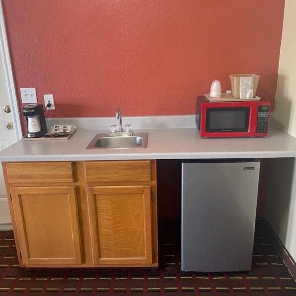 Una kitchenette compacta con un lavamanos, un microondas y un refrigerador.