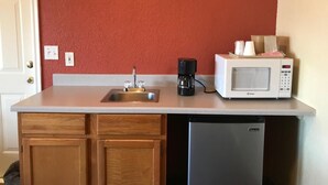 A compact kitchen with a sink, coffee maker, microwave, and dishwasher. - Budget Inn Madill (Madill)
