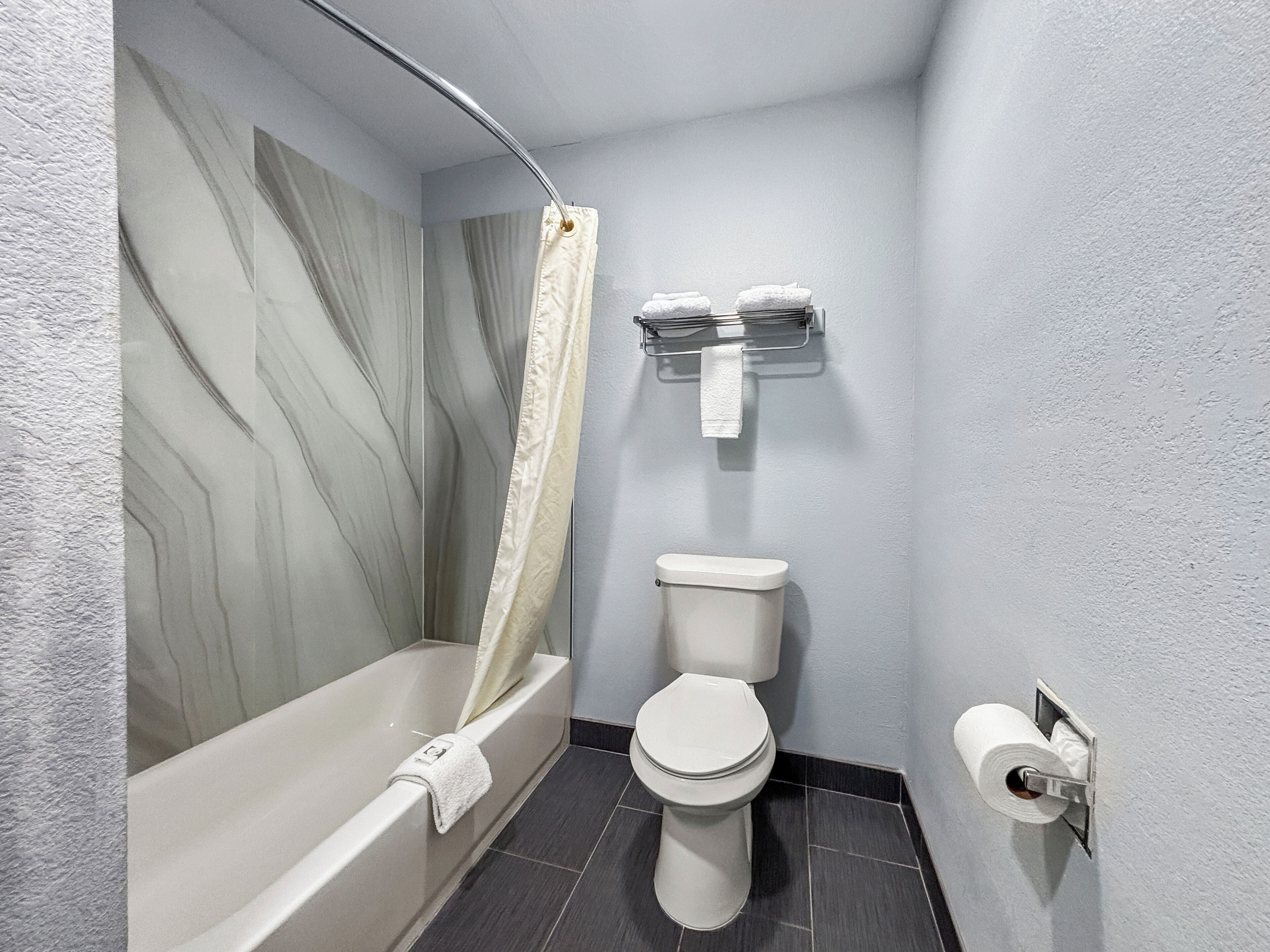 A bathroom with a bathtub, toilet, and a shower curtain.