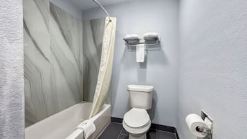 A bathroom with a bathtub, toilet, and a shower curtain.