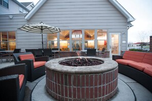 An outdoor seating area with a fire pit, wicker furniture, and an umbrella.