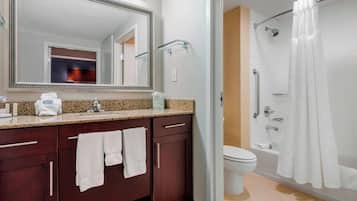 Un baño con un espejo grande, un lavabo con encimera de granito, un inodoro y una ducha con cortina blanca.