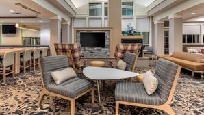 A spacious hotel lobby with a high ceiling, a central seating area with plaid chairs, a flat-screen TV, and a fireplace. - Residence Inn By Marriott Columbus (Columbus)