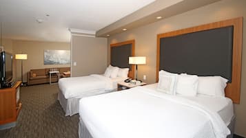 A hotel room with two beds, a TV, a sofa, and a lamp.