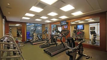 Un gimnasio con cintas de correr, elípticas y máquinas de pesas.
