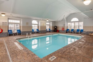 Una piscina interior con agua cristalina, líneas de profundidad marcadas y sillas azules a lo largo de los bordes.
