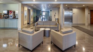 A modern lobby with a seating area, a coffee station, and an elevator.