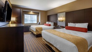 A hotel room with two beds, a TV, a window with blinds, and a striped carpet.