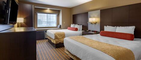 A hotel room with two beds, a TV, a window with blinds, and a striped carpet.