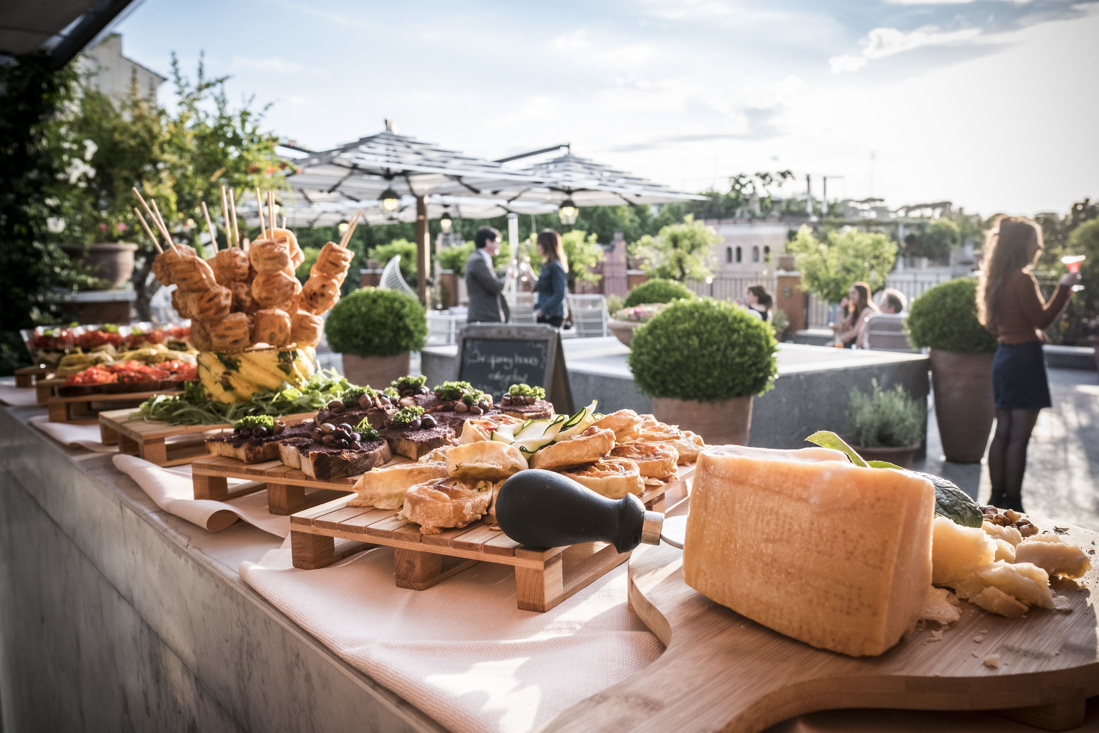 A food display with various cheeses and meats, wooden serving boards, and a chalkboard sign.