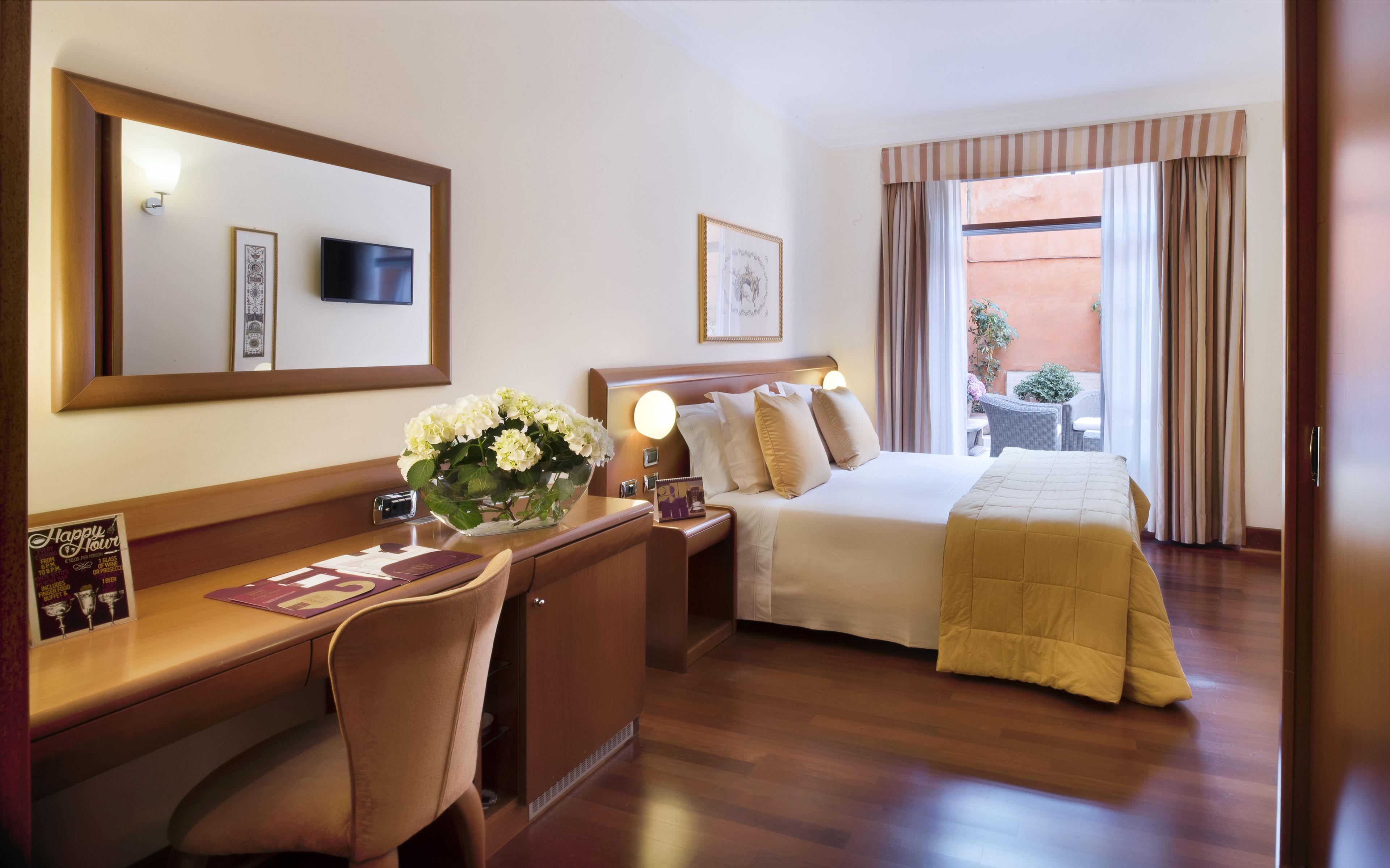 A hotel room with a bed, desk, chair, and a view of the outside.
