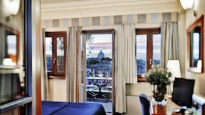 A hotel room with a bed, a desk, and a view of a dome building. - Hotel Ponte Sisto (Rome)