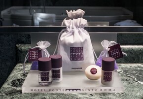A display of Hotel Ponte Sisto Roma amenities including a body lotion, shampoo, and bath foam.