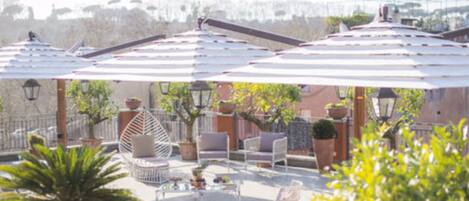 A rooftop terrace with outdoor seating, umbrellas, and potted plants.