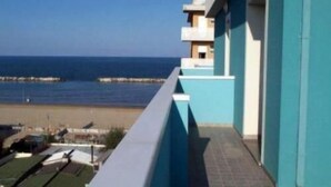 A balcony with a view of the sea and a building with a light blue facade. - Residence Beach Paradise (Rimini)